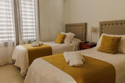雷孔基斯塔ALTA VISTA APART HOTEL的一间卧室配有两张带黄色枕头的床