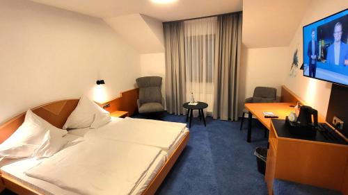 莱茵河畔凯尔Hotel Schwanen的酒店客房配有一张床、一张书桌和一台电视。