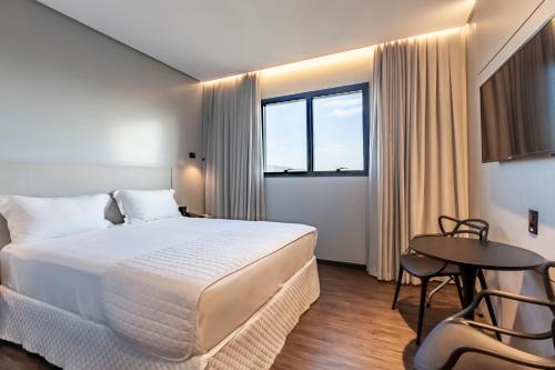 伊塔佩马Tri Hotel Premium Itapema的酒店客房设有一张大床和一张桌子。