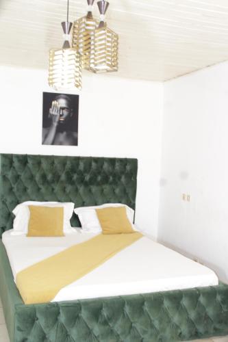 雅温得KRISTAL HOME的一间卧室配有一张大床和绿色床头板