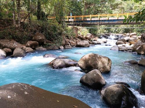 San RafaelCabaña bosque río celeste的一条有岩石的河流和一座有火车的桥梁