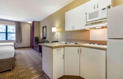 斯普林代尔Extended Stay America Select Suites - Fayetteville - Springdale的一间带白色橱柜的厨房和一间带一张床的房间