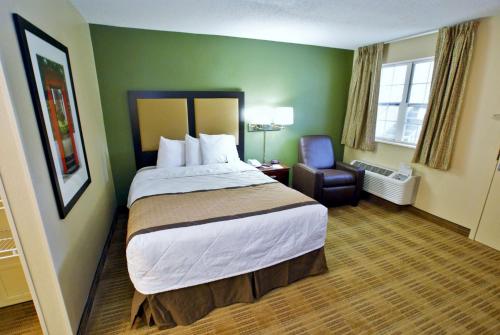 莱克伍德Extended Stay America Select Suites - Denver - Lakewood South的酒店客房带一张大床和一把椅子
