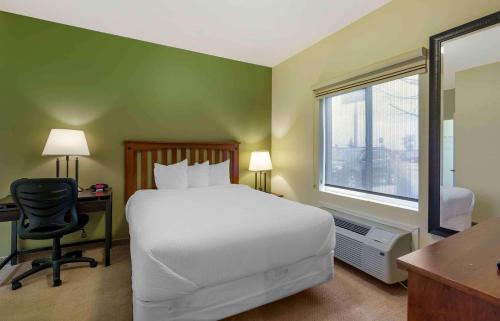 迈诺特Extended Stay Americas Suites - Minot的一间卧室配有一张床、一张书桌和一个窗户。