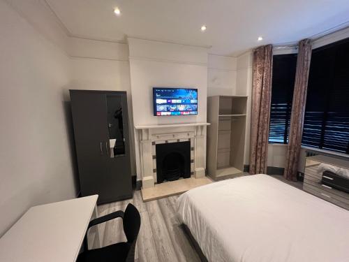 克罗伊登Rooms in Modernised Victorian House的一间卧室设有两张床、一台电视和一个壁炉