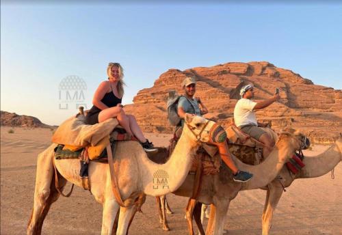 瓦迪拉姆Lma Luxury Camp的三个人骑在沙漠骆驼后面