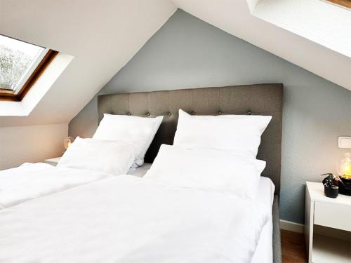 门兴格拉德巴赫Modernes City-Apartment in Mönchengladbach的阁楼卧室设有两张床,配有白色枕头
