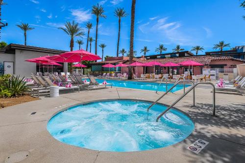 棕榈泉The Paloma Resort的一个带椅子和粉红色遮阳伞的游泳池