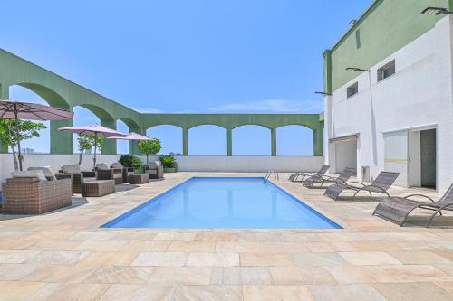 里梅拉Hotel Nacional Inn Limeira的一个带椅子和遮阳伞的庭院内的游泳池