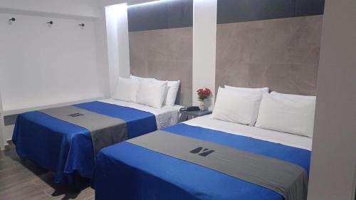 韦拉克鲁斯Hotel GALENO的蓝色和白色的客房内的两张床
