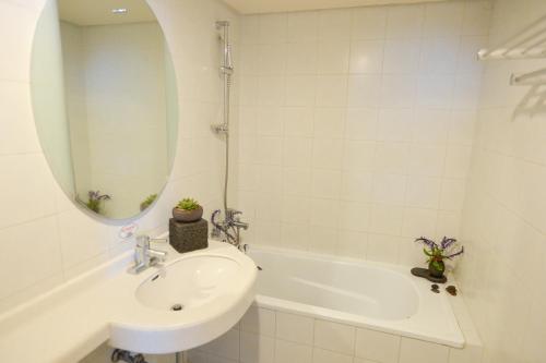 济州市大同酒店的一间带水槽、浴缸和镜子的浴室