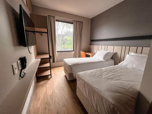 加里波第Plaza Hotel & Boulevard Convention - Vale dos Vinhedos的酒店客房设有两张床和窗户。