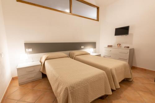 利斯西亚迪维卡Nuovi Appartamenti Tri e Bilocali in Residence con Piscina a Porto Cervo 800mt Mare的一间卧室设有两张床,墙上配有电视。