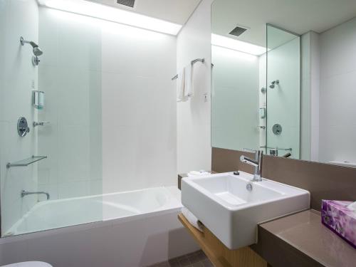 布莱克敦东克里克阿尔法酒店的浴室配有水槽、淋浴和浴缸。