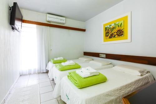 伊瓜苏达曼酒店的一间设有三张床的客房,配有绿色毛巾