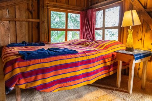 圣克鲁斯拉拉古纳La Iguana Perdida的木质客房里一张色彩缤纷的床,设有窗户