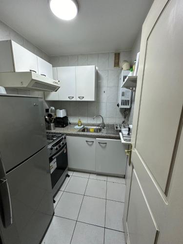 圣地亚哥Depto Las Condes- Est Español的小厨房配有白色橱柜和冰箱。