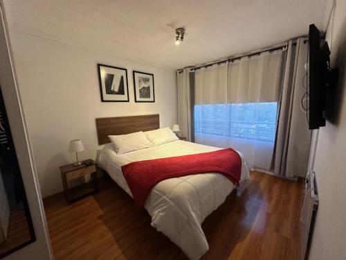圣地亚哥Depto Las Condes- Est Español的一间卧室配有一张带红色毯子的床和窗户。