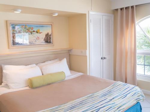 Creek VillagePerfect Island Retreat at Paradise Island Beach Club Villas的卧室配有带白色枕头的床和窗户。