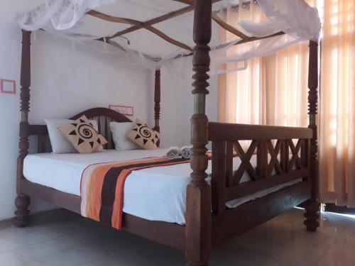 坦加拉Sasagara Beach Villa的卧室配有带白色床单的木制天蓬床
