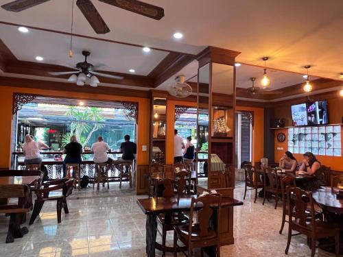 芭东海滩Nanai 2 Residence Patong Phuket的一间设有桌子的餐厅,有坐在桌子上的人