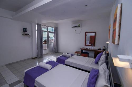 希克杜沃Hotel Wewala Beach的一间卧室设有两张床和窗户。