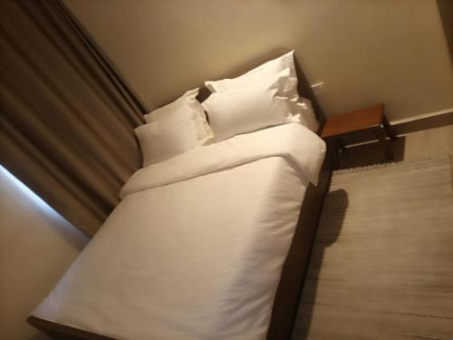 NarokLux Suites Narok Holiday Homes的一张带白色床单和枕头的小床