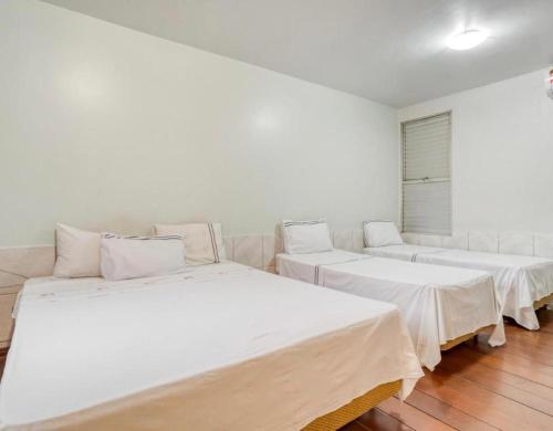 戈亚尼亚Itajubá Classic Hotel Goiânia的配有白色墙壁和木地板的客房内的三张床