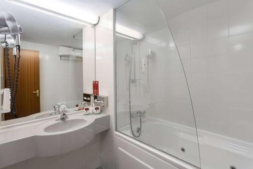 布加勒斯特Ramada by Wyndham Bucharest Parc Hotel的白色的浴室设有水槽和淋浴。