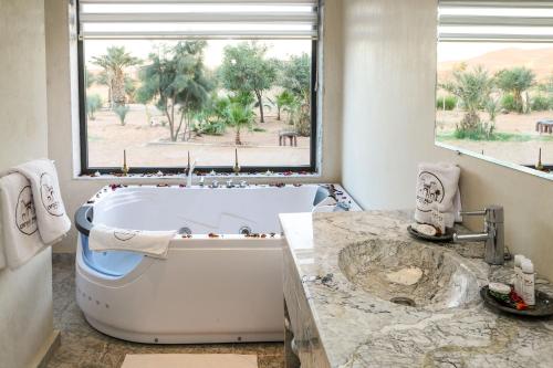 梅尔祖卡Yakout Merzouga Luxury Camp的带浴缸的浴室和大窗户