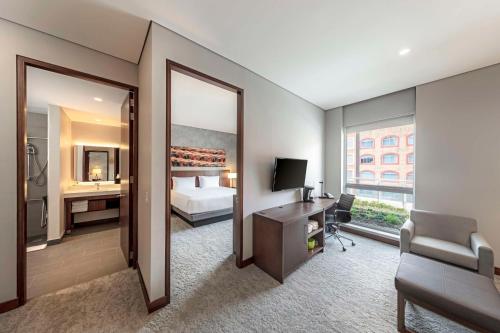 波哥大Hyatt Place Bogota Convention Center的酒店客房带一张床、一张书桌和一面镜子