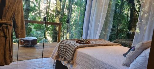 弗洛里亚努元帅镇TreeHouse Seu Paraíso nas Montanhas的卧室设有一张位于大窗户前的床铺。