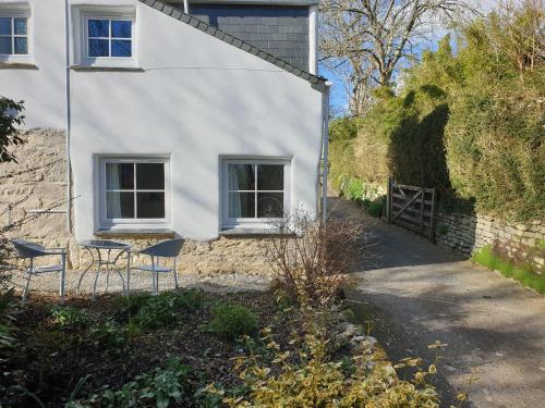 赫尔斯顿Primrose Cottage的前面有两把椅子的白色房子