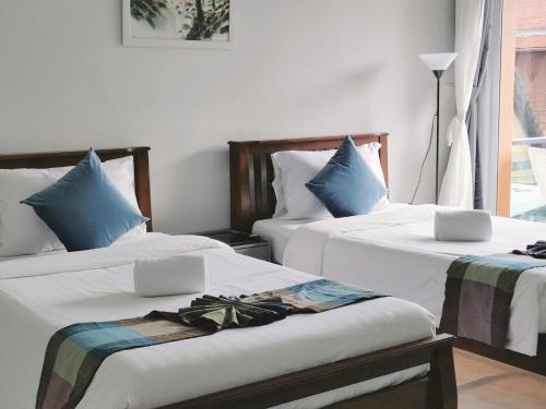 卡马拉海滩Sasimanta的一间卧室配有两张带白色床单和蓝色枕头的床。