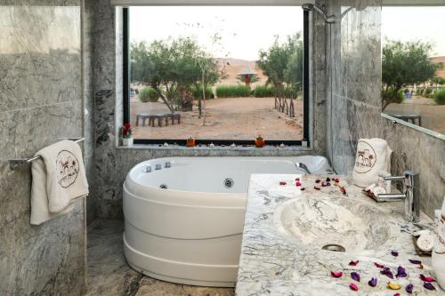 梅尔祖卡Yakout Merzouga Luxury Camp的带浴缸的浴室和大窗户