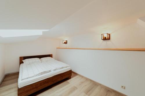 斯皮什斯凯波德赫拉杰Ubytovanie Starý dvor的白色墙壁和木地板的客房内的一张床位