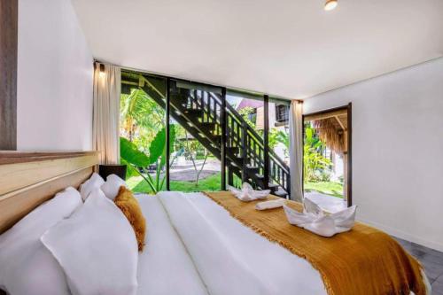 坎古Belvilla Seaside Hermitage Cosy Bungalow Canggu Beach的一间卧室设有一张大床和大窗户