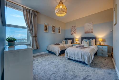 朴次茅斯Modern 2-Bed Stylish Contractor House, Prime Portsmouth Location & Parking - By Blue Puffin Stays的一间卧室设有两张床和窗户。