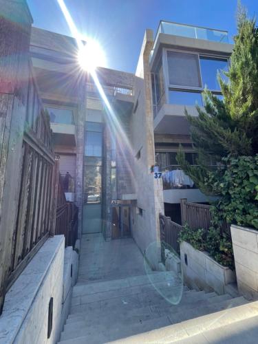 安曼Abdoun Falls Luxury Apartment的阳光照耀着窗外的房子