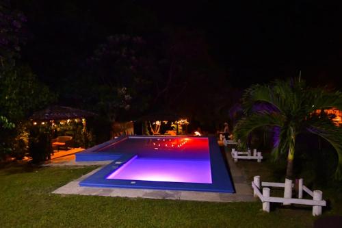 格拉西亚斯Cabaña Villa de Ada的游泳池在晚上,周围设有两个白色长椅