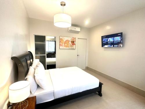 莫阿尔博阿HARMAN SUITES Moalboal的卧室配有白色的床和平面电视。