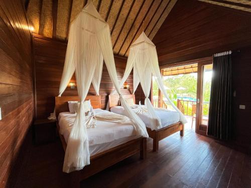 蓝梦岛Sunset Hill Lembongan的一间卧室配有两张床和蚊帐