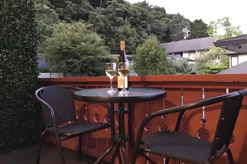 派西亚The Swiss Chalet Holiday Apartment 6, Bay of Islands的阳台上的桌子和两杯葡萄酒