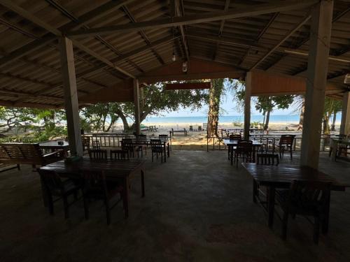 昌岛Changthong Bungalow的一间空荡荡荡的餐厅,配有桌椅和海滩