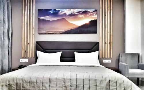新德里Airport Hotel Delhi Aerocity的卧室配有一张床,墙上挂有绘画作品