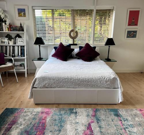 Sole StreetTHE HIDEAWAY - KENT的卧室配有一张带紫色枕头的大型白色床。