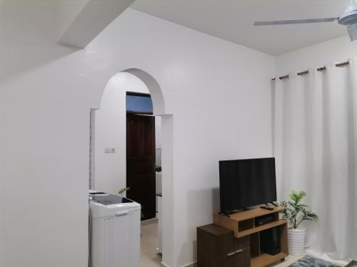 蒙巴萨Millan Homes的一间客厅,在白色的墙上配有电视