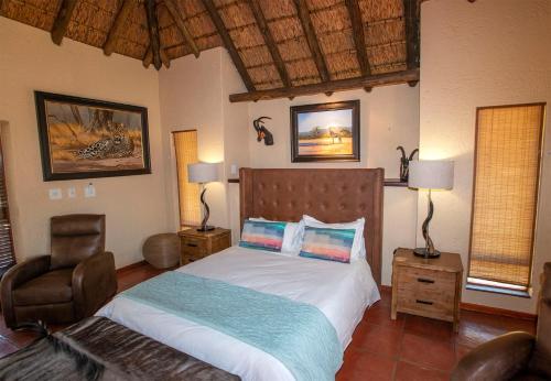 法尔瓦特Ilanga Safari Lodge - Welgevonden Game Reserve的一间卧室配有一张床和一把椅子