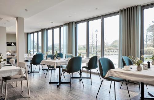 瓦尔内明德Baltic Hideaways Beach Hotel Warnemünde的餐厅设有桌椅和大窗户。