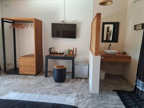 拉迈Laura Guest House Samui的客房设有水槽、书桌和电视。